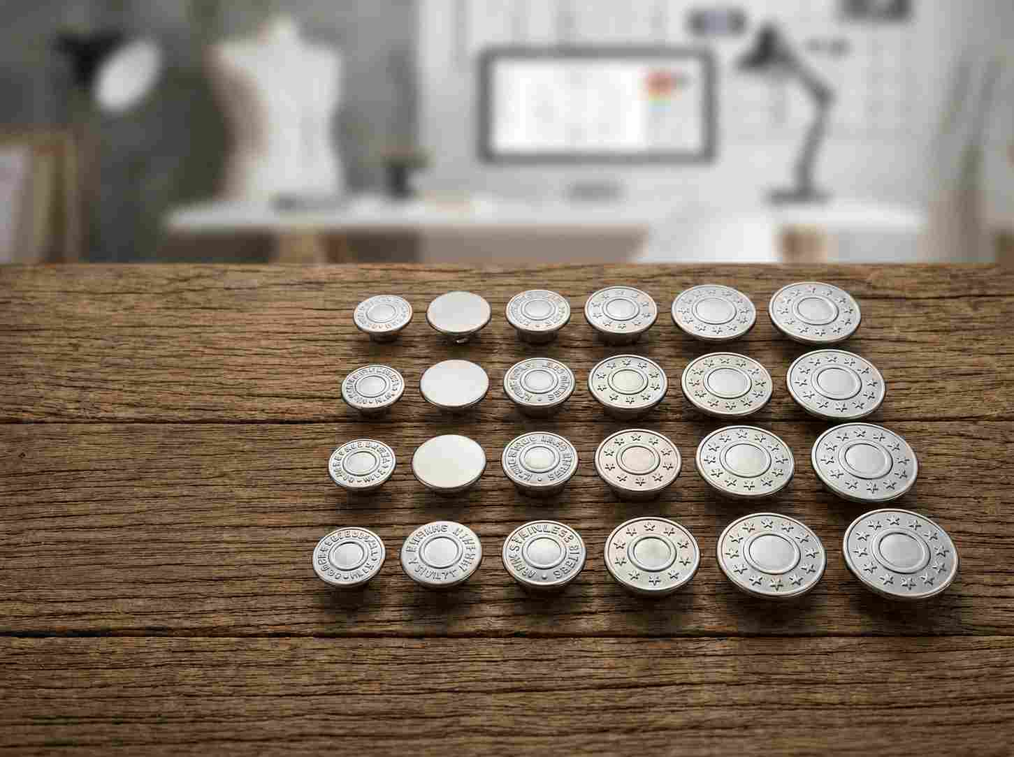 mens jeans button, Mens jeans button samples in different sizes and embossed designs are arranged in rows on a wooden table.